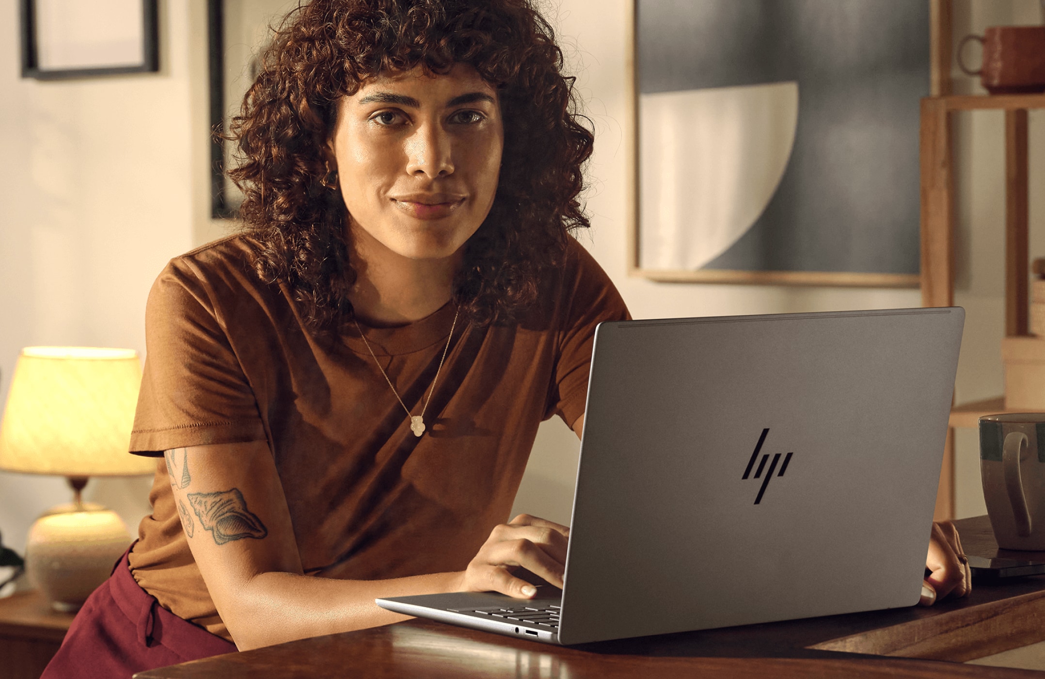 Woman working on an HP laptop aside a cup of coffee