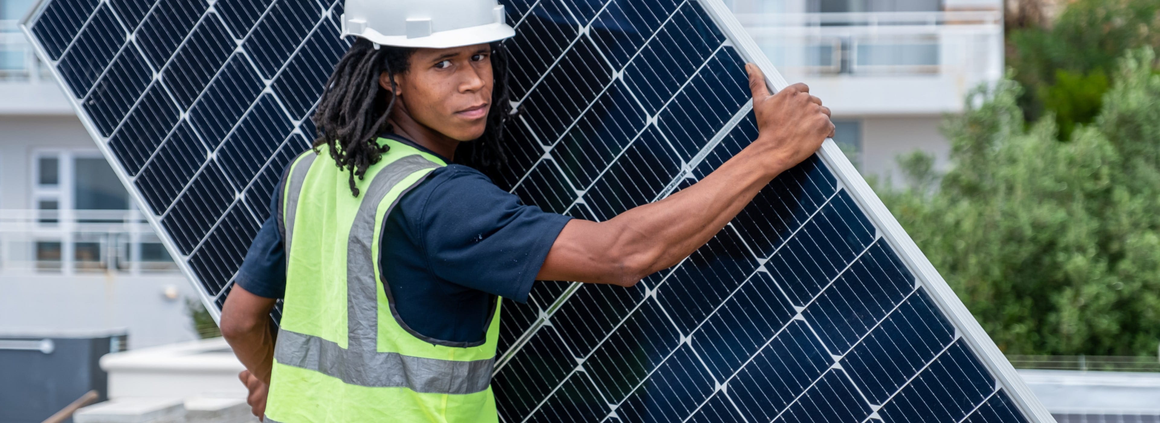 A worker carrying a big solar panel for installation.