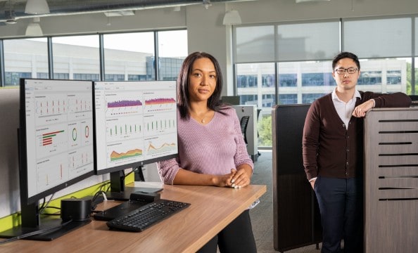 Two employees standing aside two HP monitors connected to an HP dock.