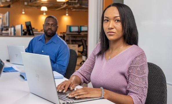 Two employees working on their HP laptops in their office.