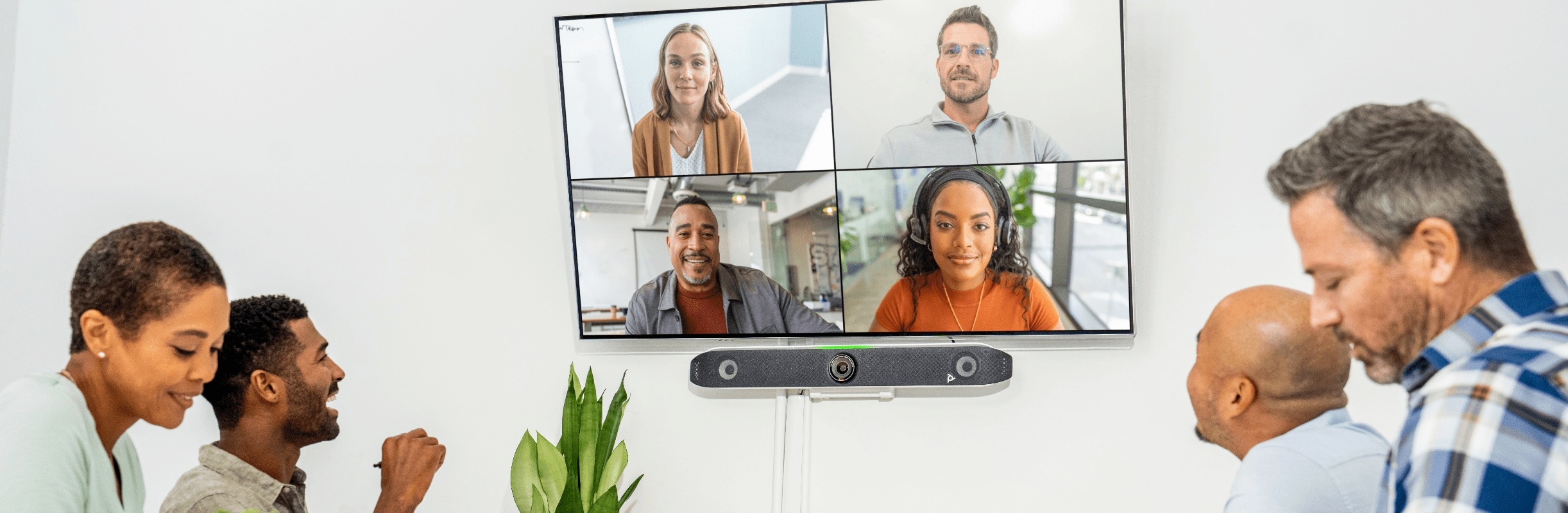 Coworkers in large conference room engaged in a video call using Poly Studio X52 all-in-one video bar