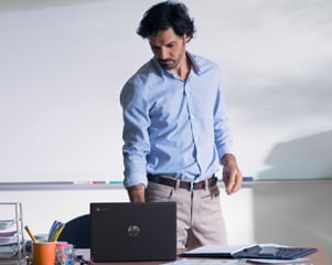 A man working on his HP Chrome computer laptop in a classroom.