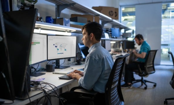 A man working on two HP monitors connected to an HP dock.