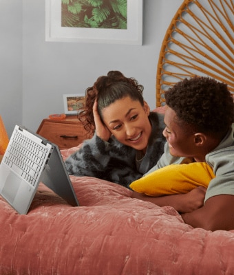 Girl and boy on the bed, looking at laptop screen in tent mode