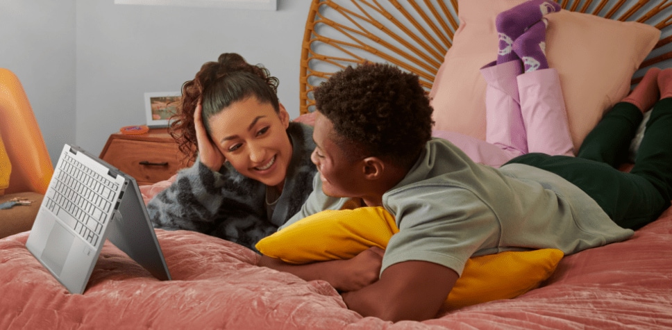 Girl and boy on the bed, looking at laptop screen in tent mode