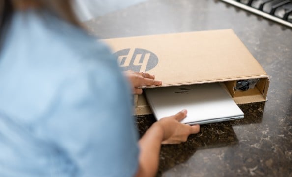 A woman pulling an HP laptop out of the box.