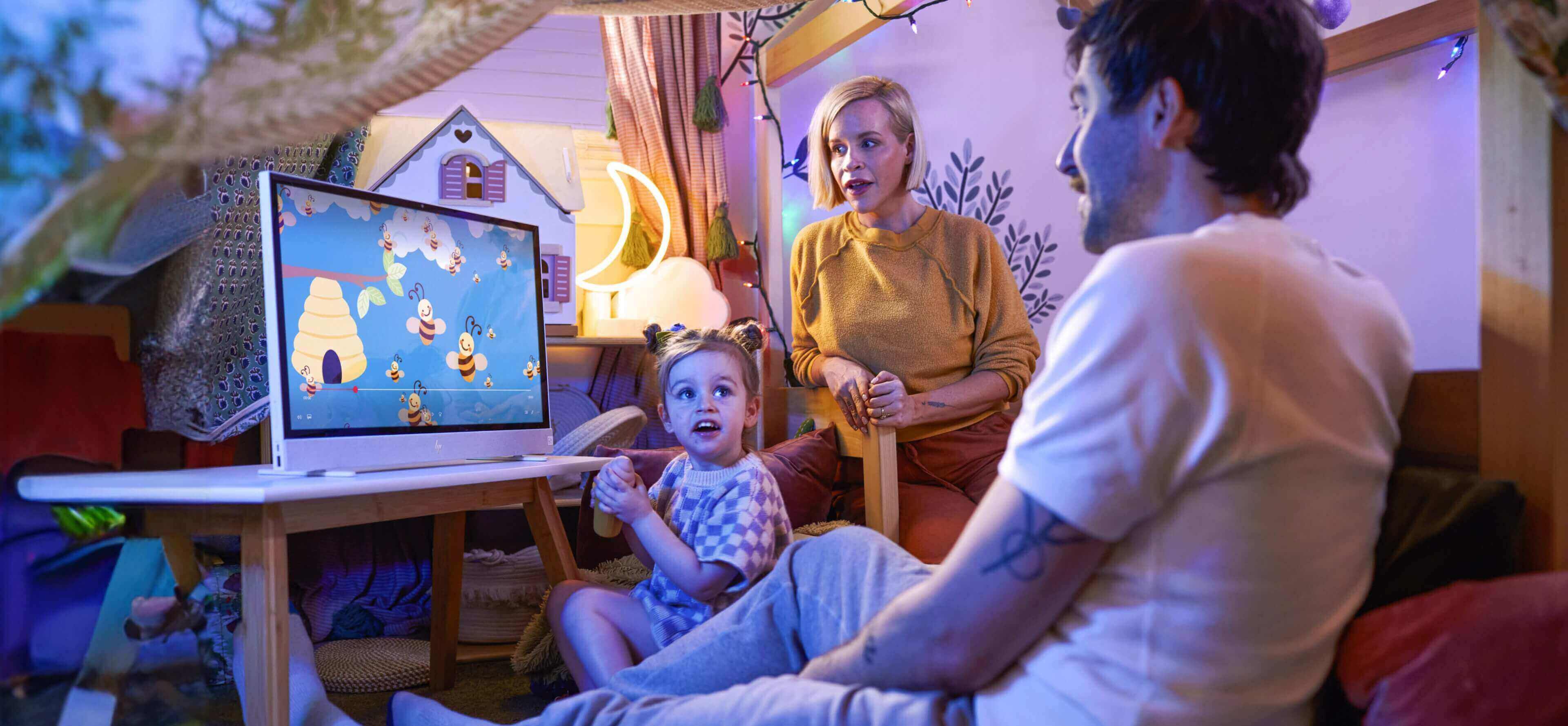 A family waitching a cartoon on an HP Move in their daughter's bedroom.