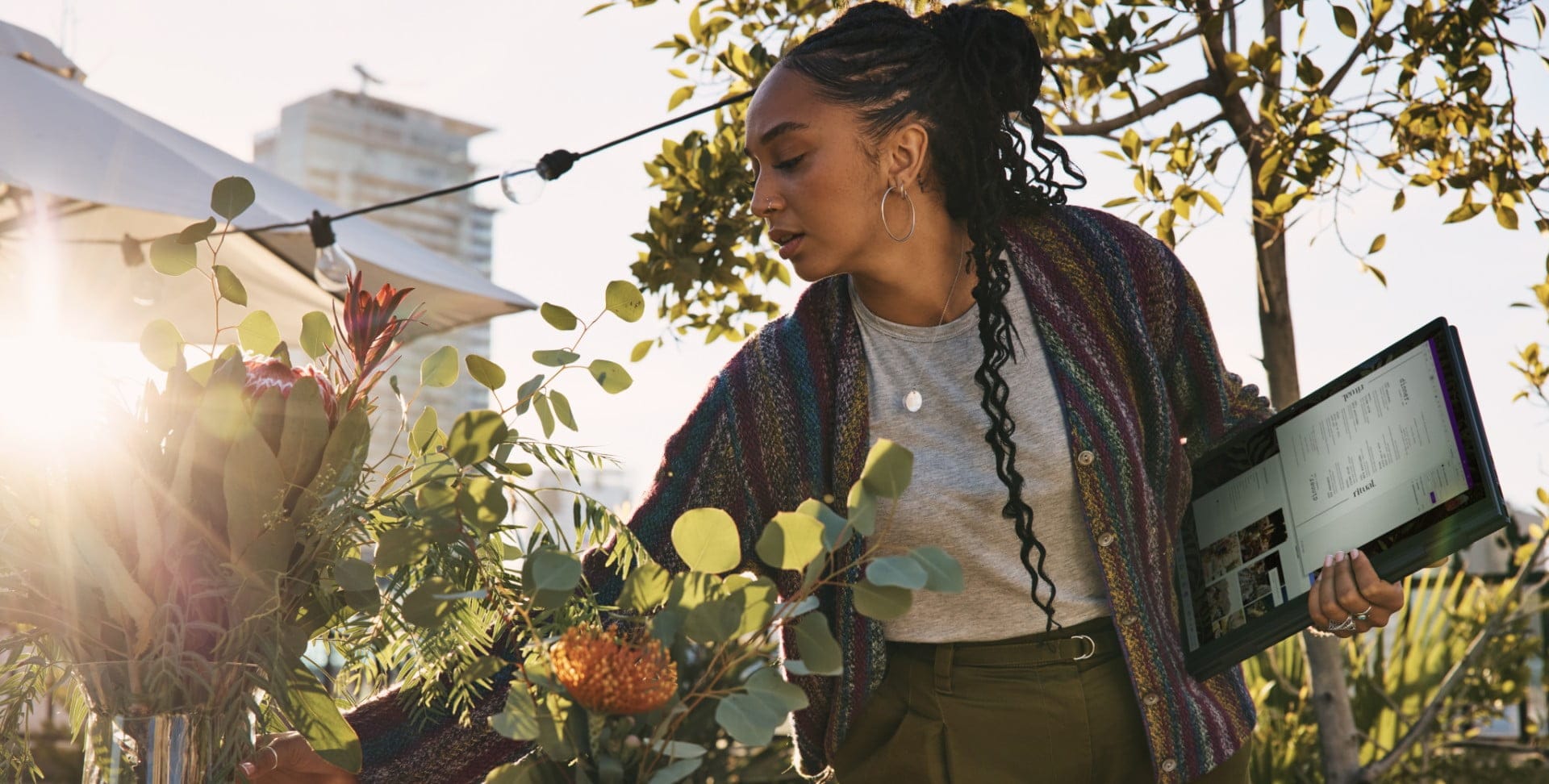 A woman working on her garden while carrying an HP laptop.