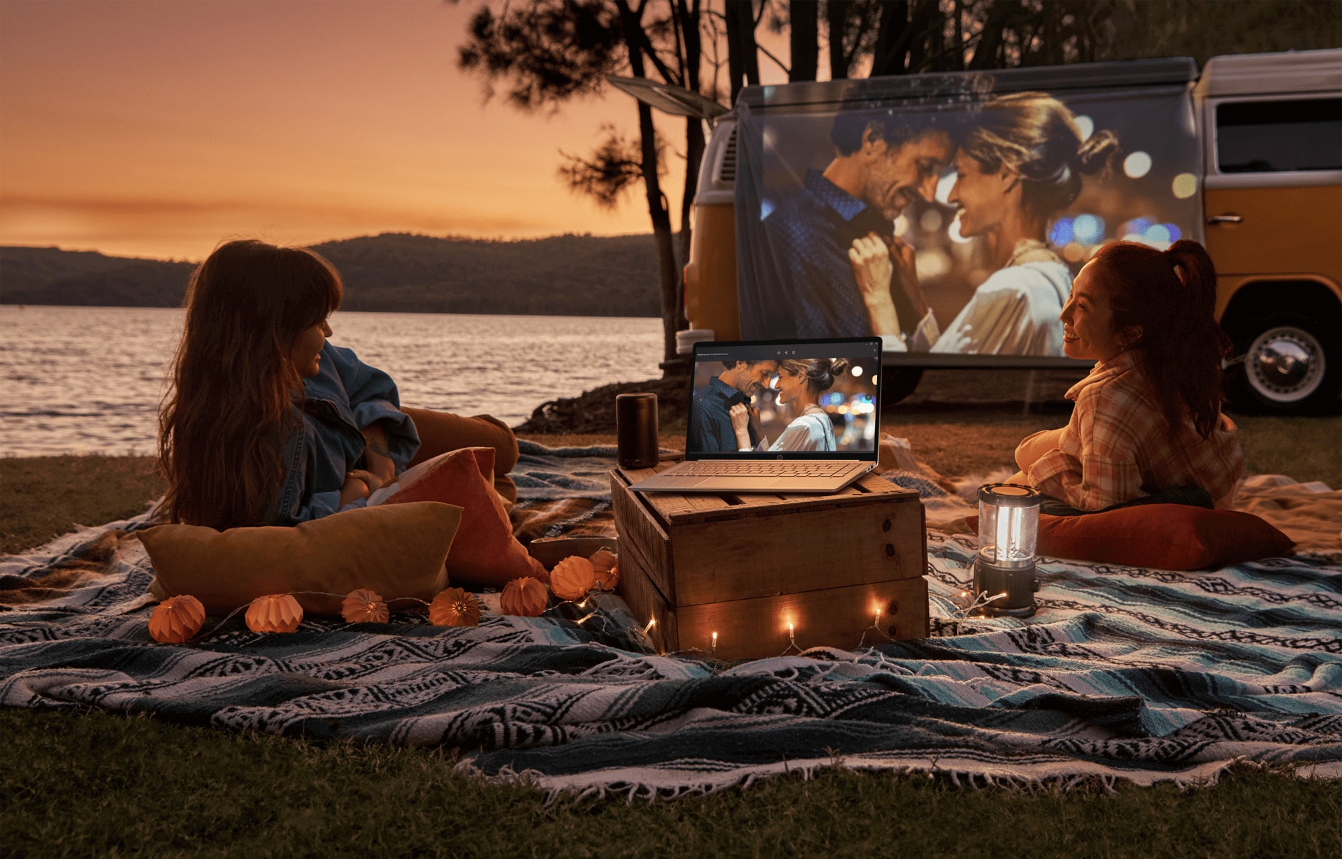 A woman laying on a beach watching a video on her HP laptop using a proyector.