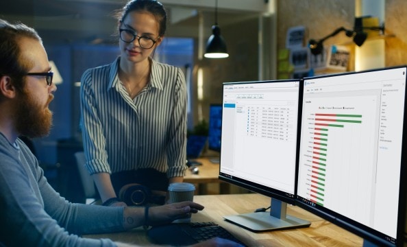 A man checking some data on his two HP monitors next to his co-worker.