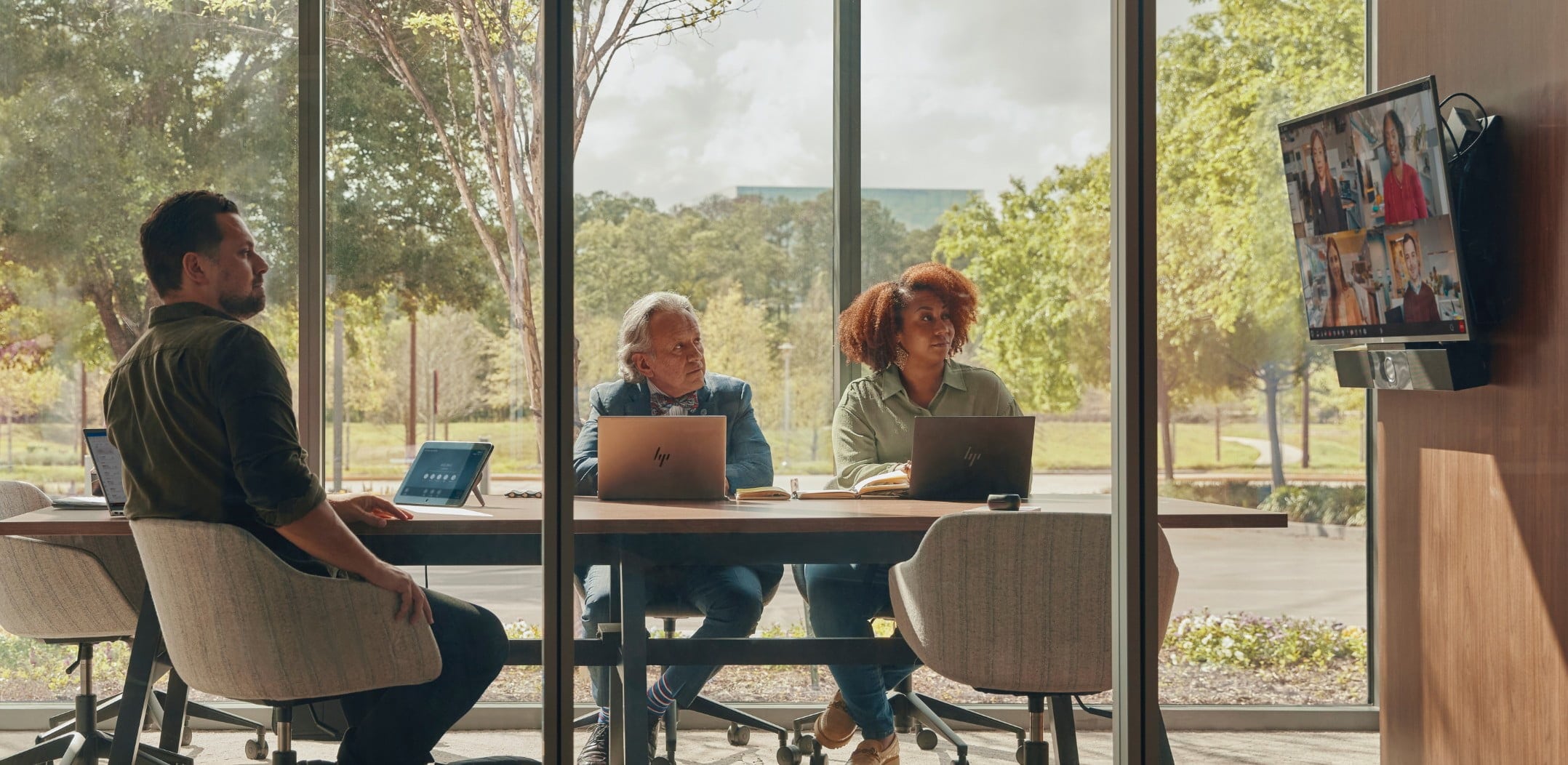 People in glass-walled conference room, engaged in a a video call using Poly Studio USB