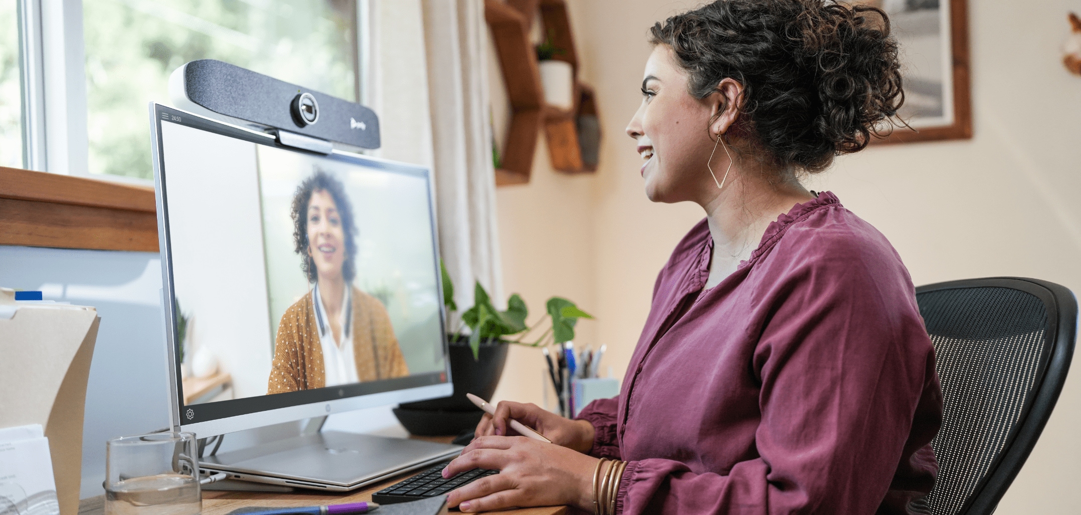 Woman seated at home office desk using Poly P15 video bar during a video conference call