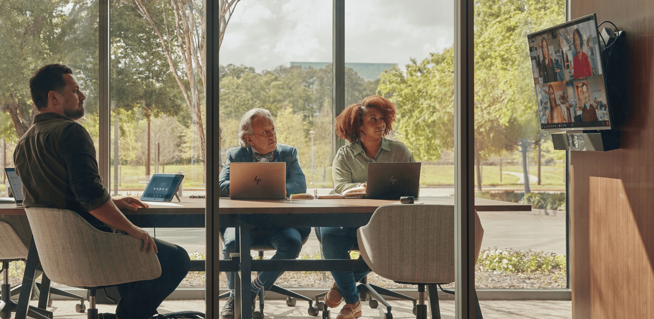 People in wall-to-wall window conference room  during video conference call using Poly Studio USB video bar