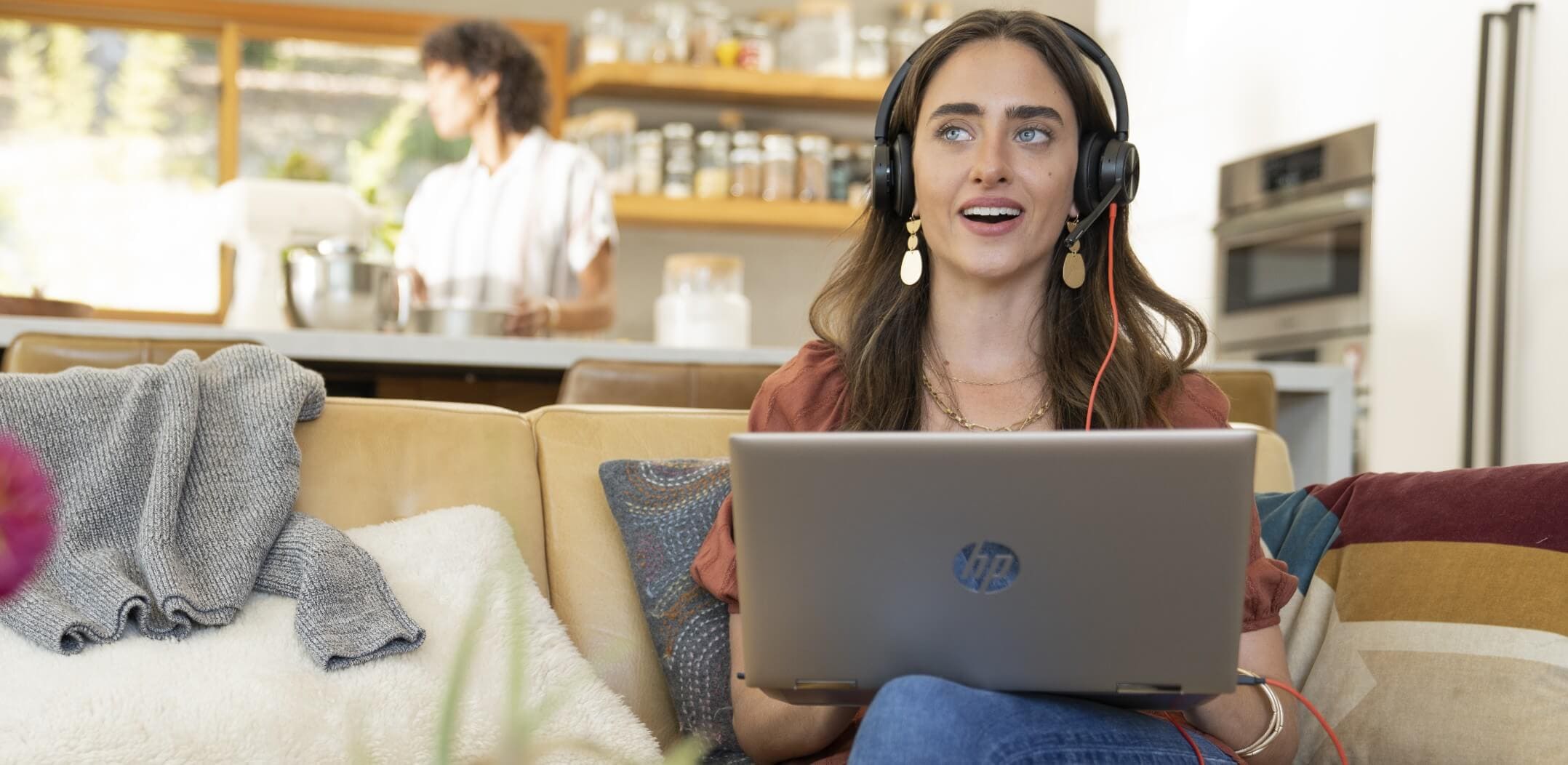 Woman working from home on sofa, using her laptop and wearing Poly Blackwire 8225 wired UC headset