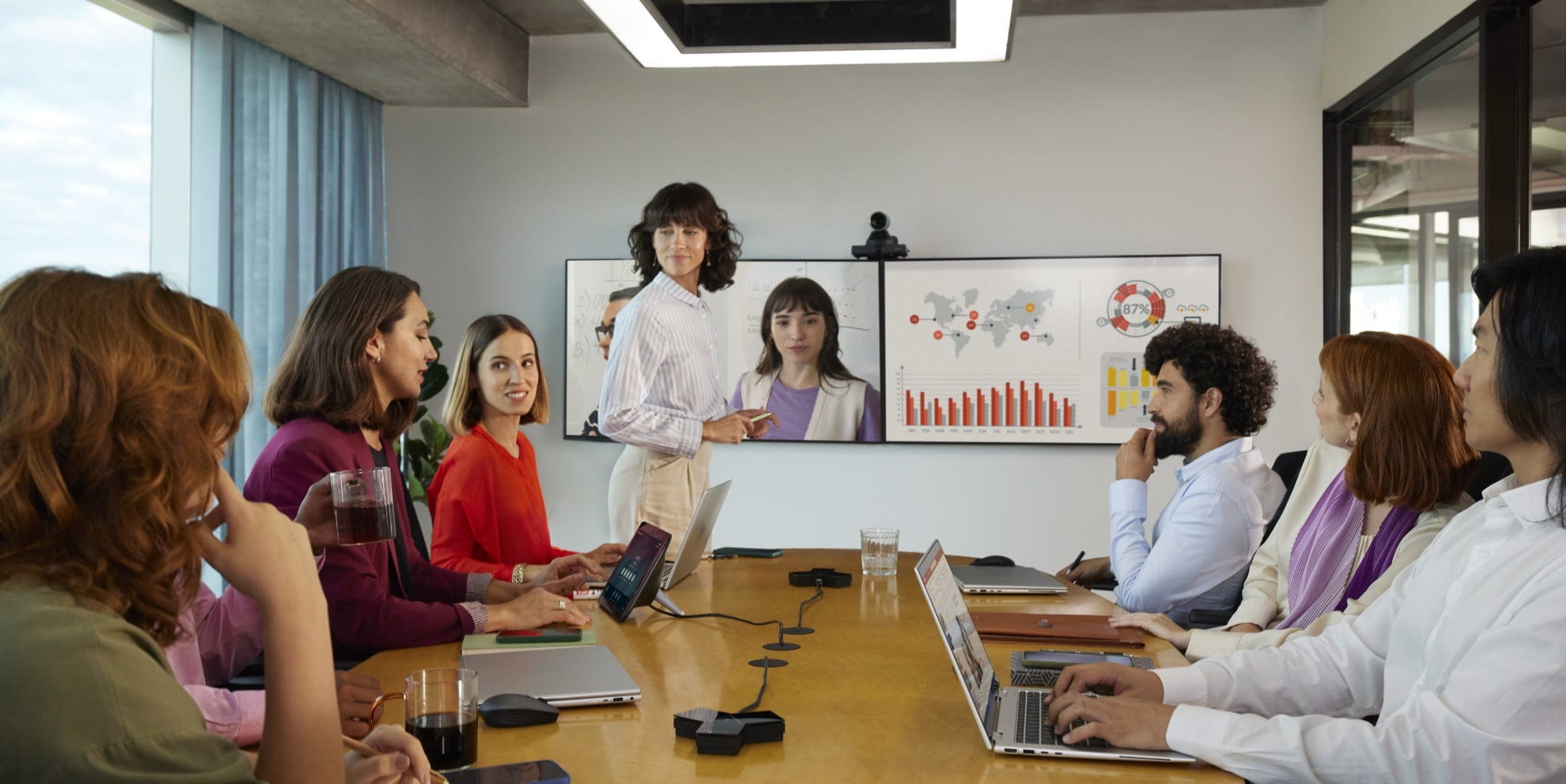 Large conference room with people engaged in a content-sharing video call using Poly Studio G7500 modular video conferencing system​