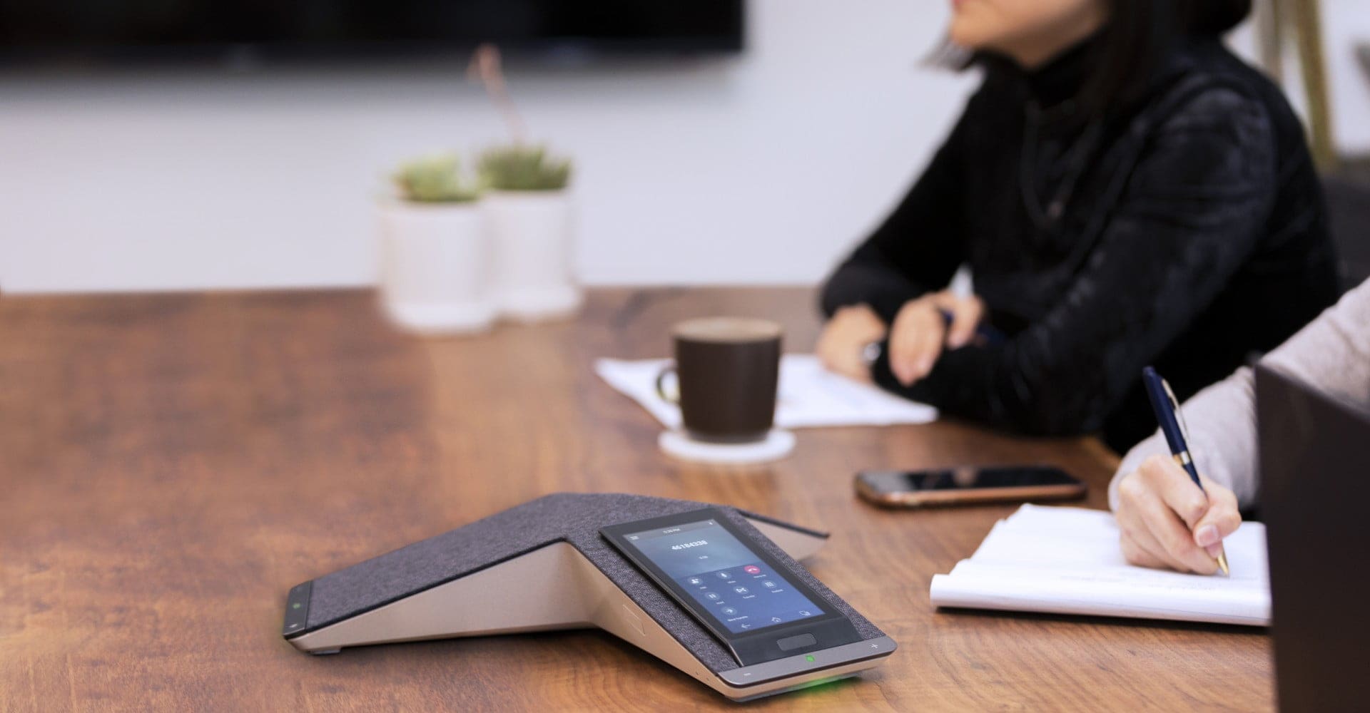 People in meeting room with Poly Trio C60 conference phone on table