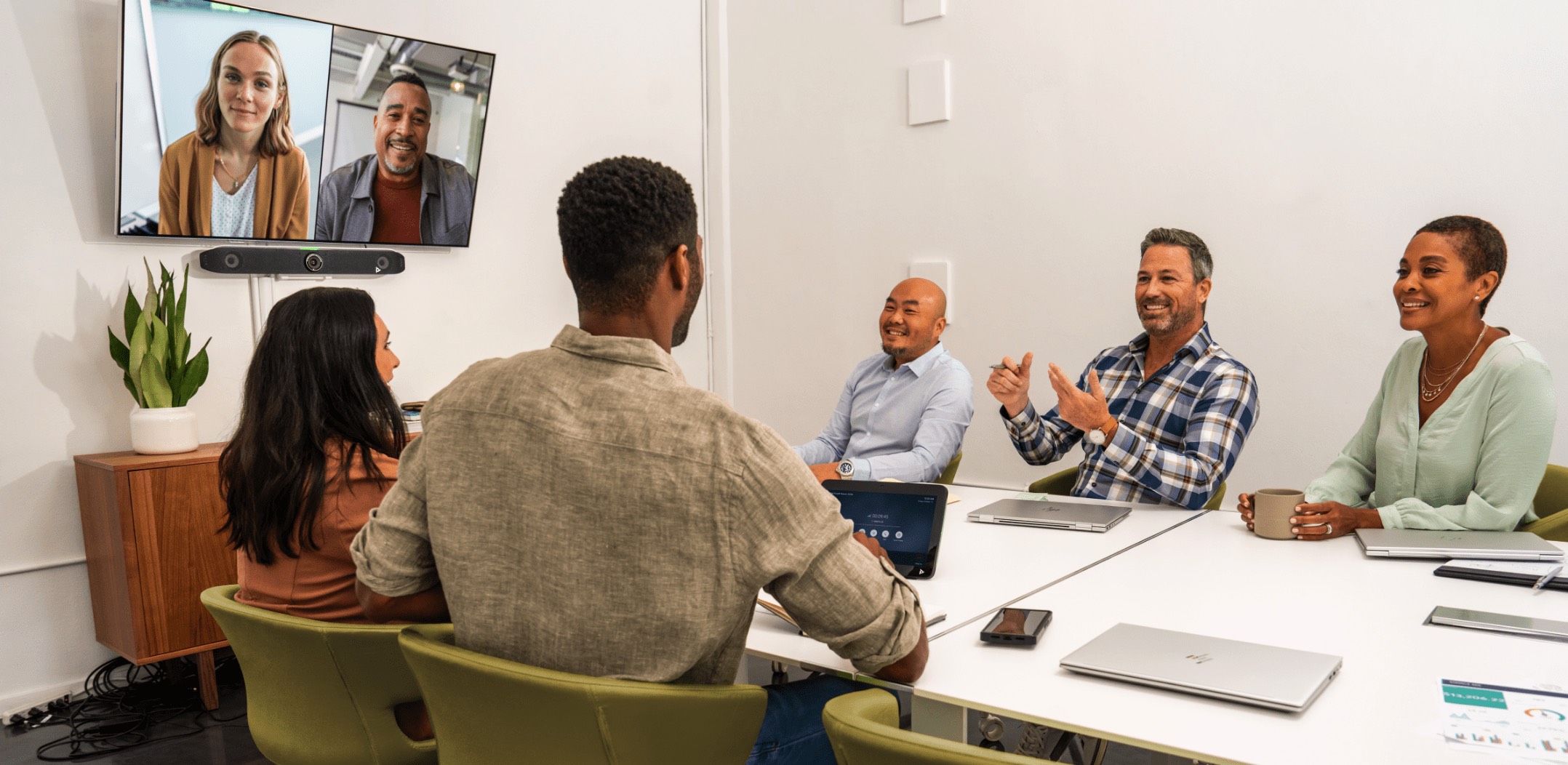 Group of people in a medium-sized conference room, engaged in a video call using the Poly Studio X52 all-in-one video bar