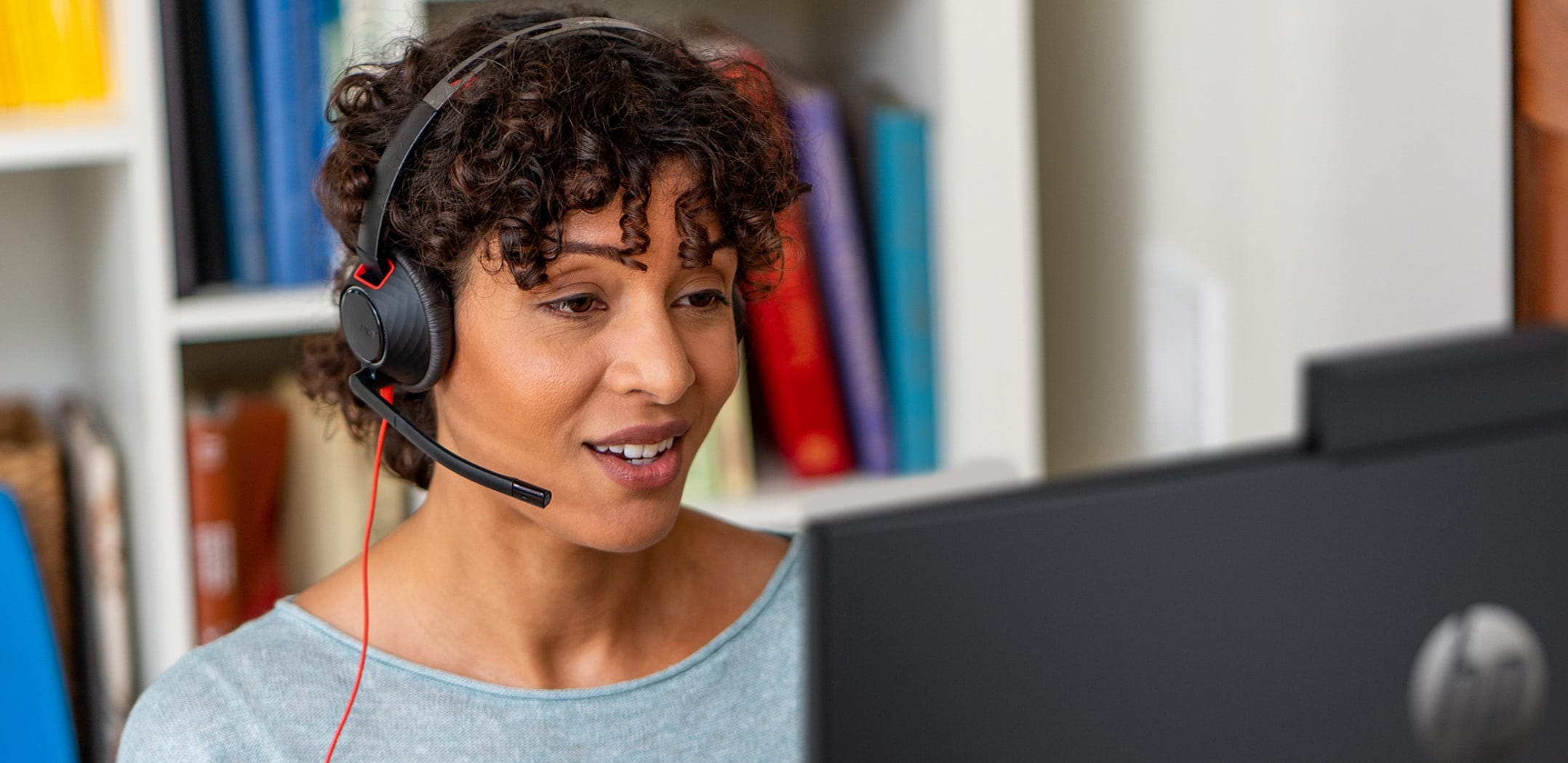 Woman in home office using Poly Blackwire 5200 USB wired headset during a video call