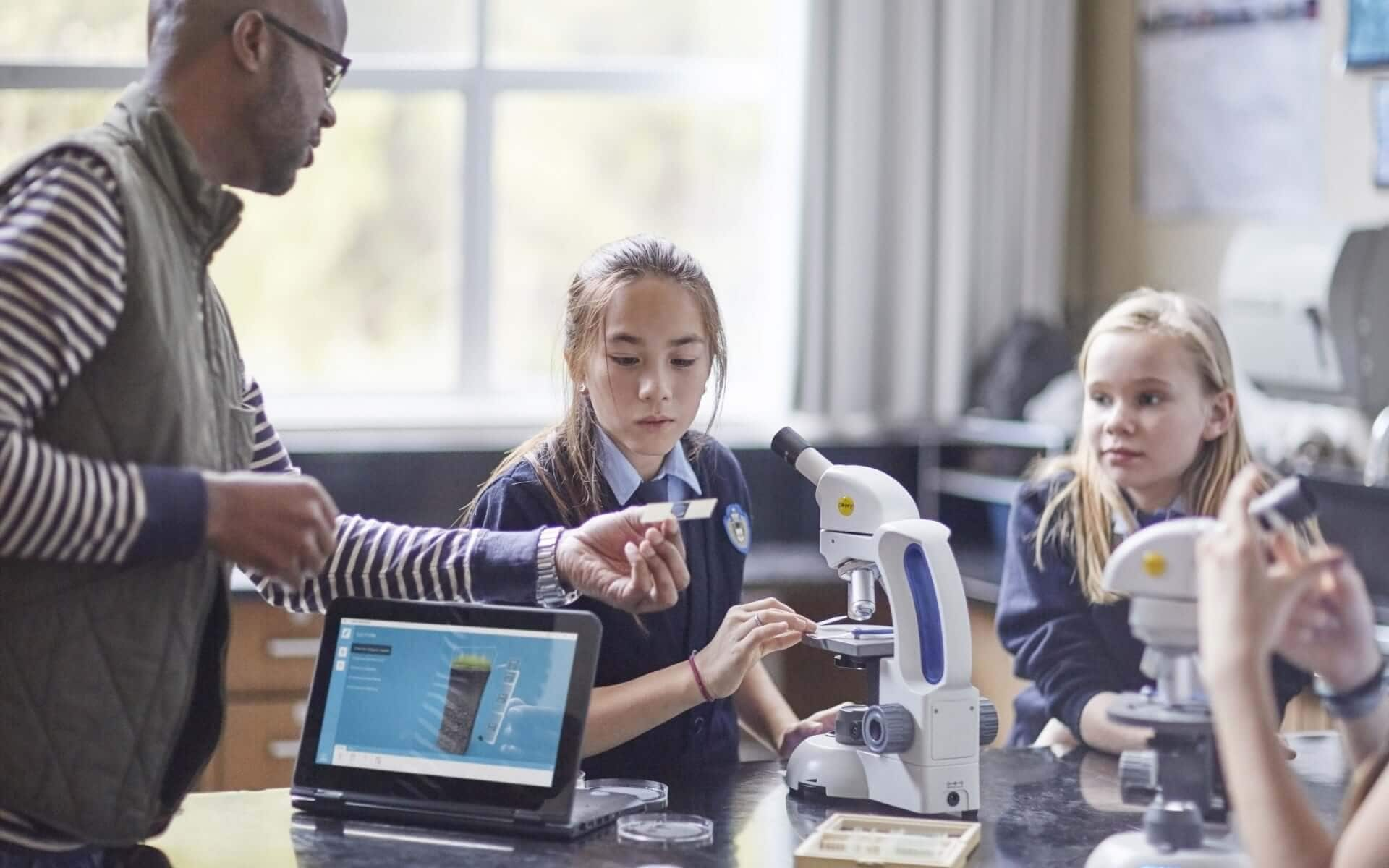 Male teacher with three young students and an HP tablet