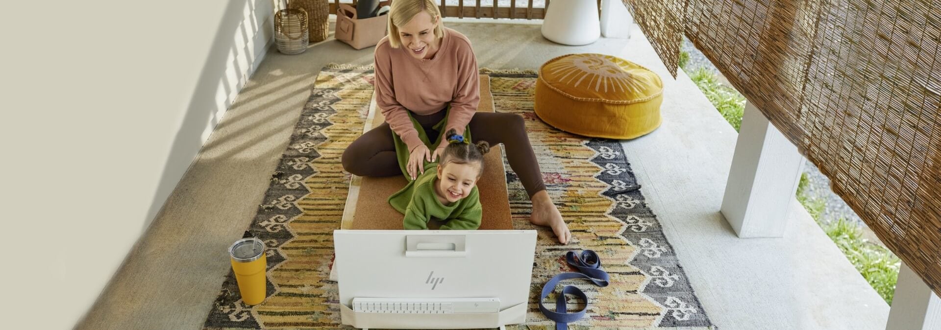 A woman with her daughter having fun watching an HP Envy All-in-One PC.