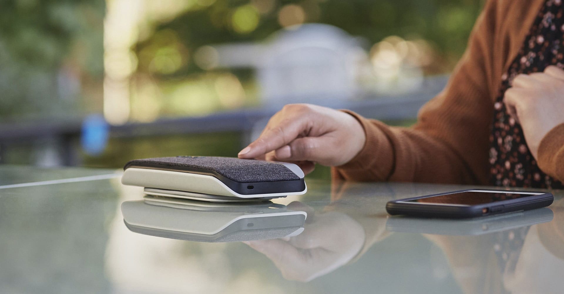 Person seated outdoors using Poly Sync 20 USB Bluetooth speakerphone