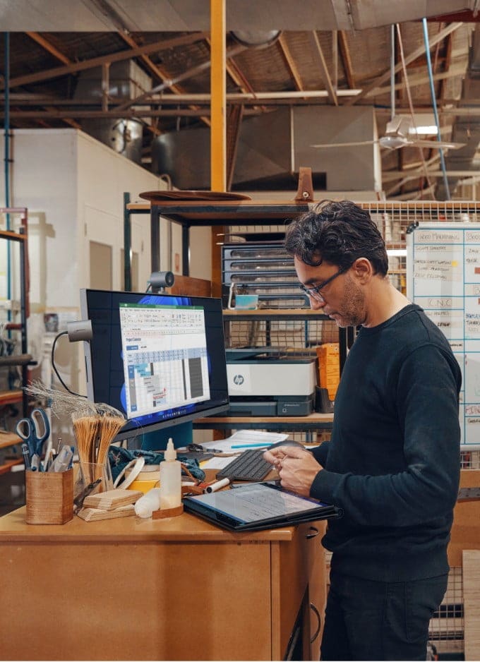 A man working on an HP 34-inch All-in-One desktop pc and with an HP laptop on tablet mode.