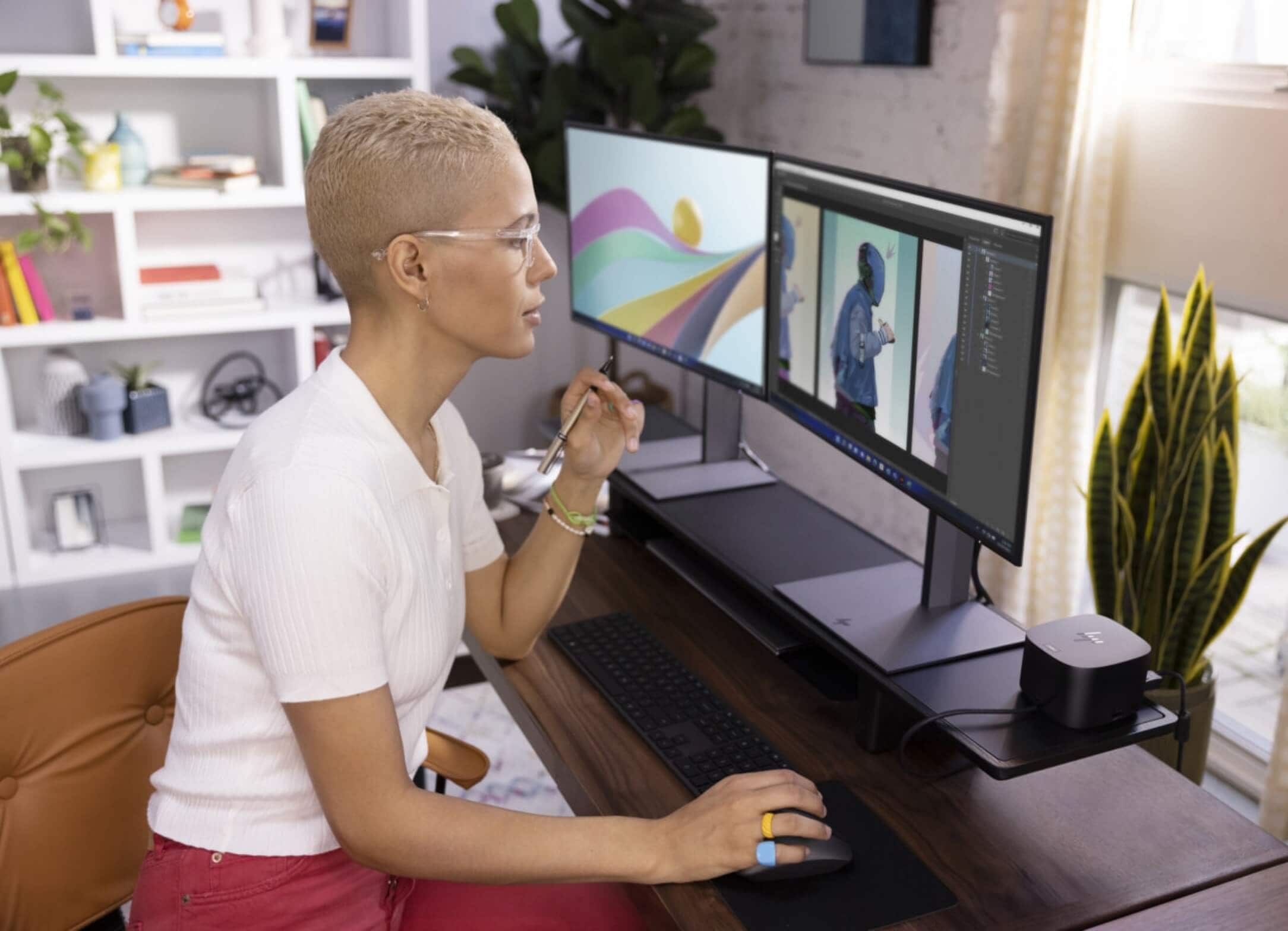 A woman editing some draws on her two HP monitors connected to an HP dock and an HP laptop.