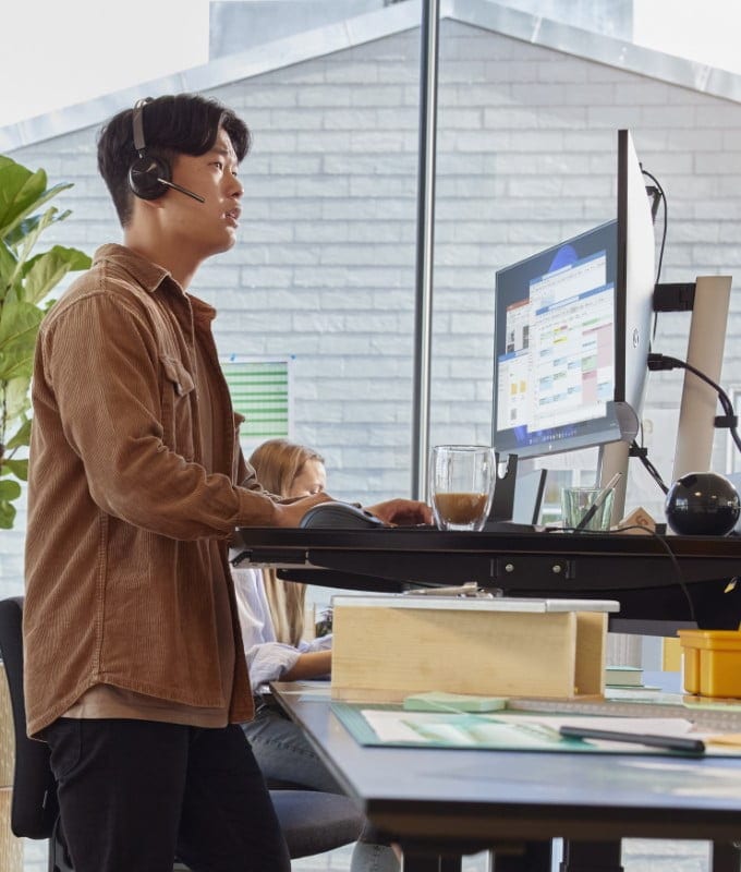 Man standing at a desk in an office with an HP ProBook laptop.