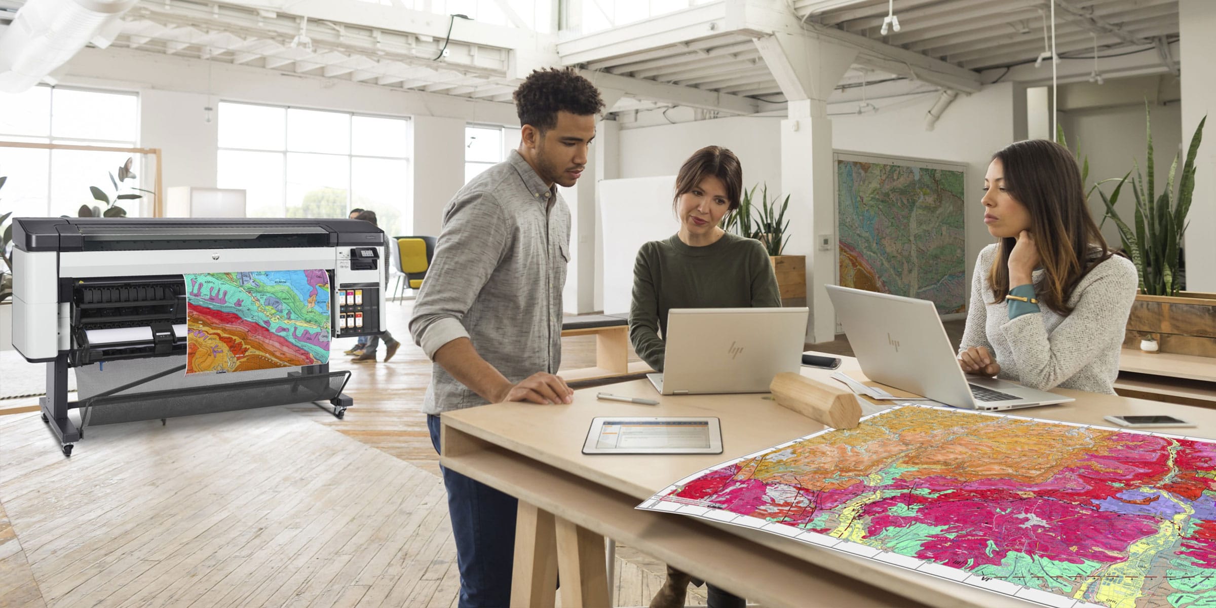 People working with prints next to an HP DesignJet plotter