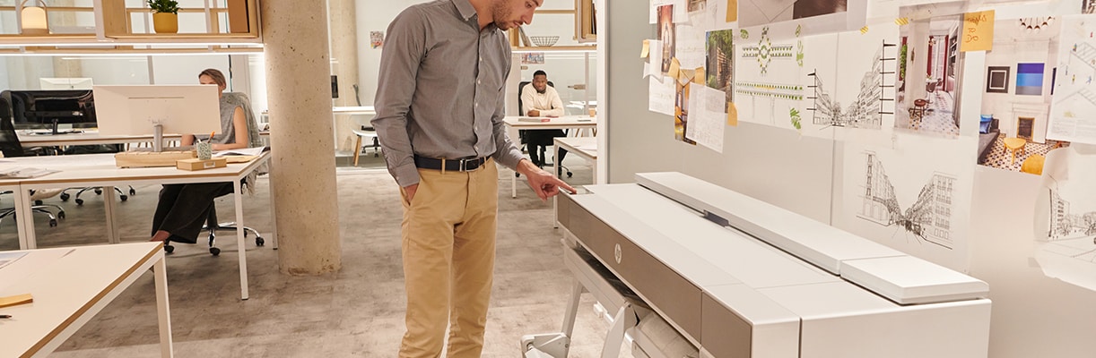 Person using the touchscreen of an HP large-format plotter in an office