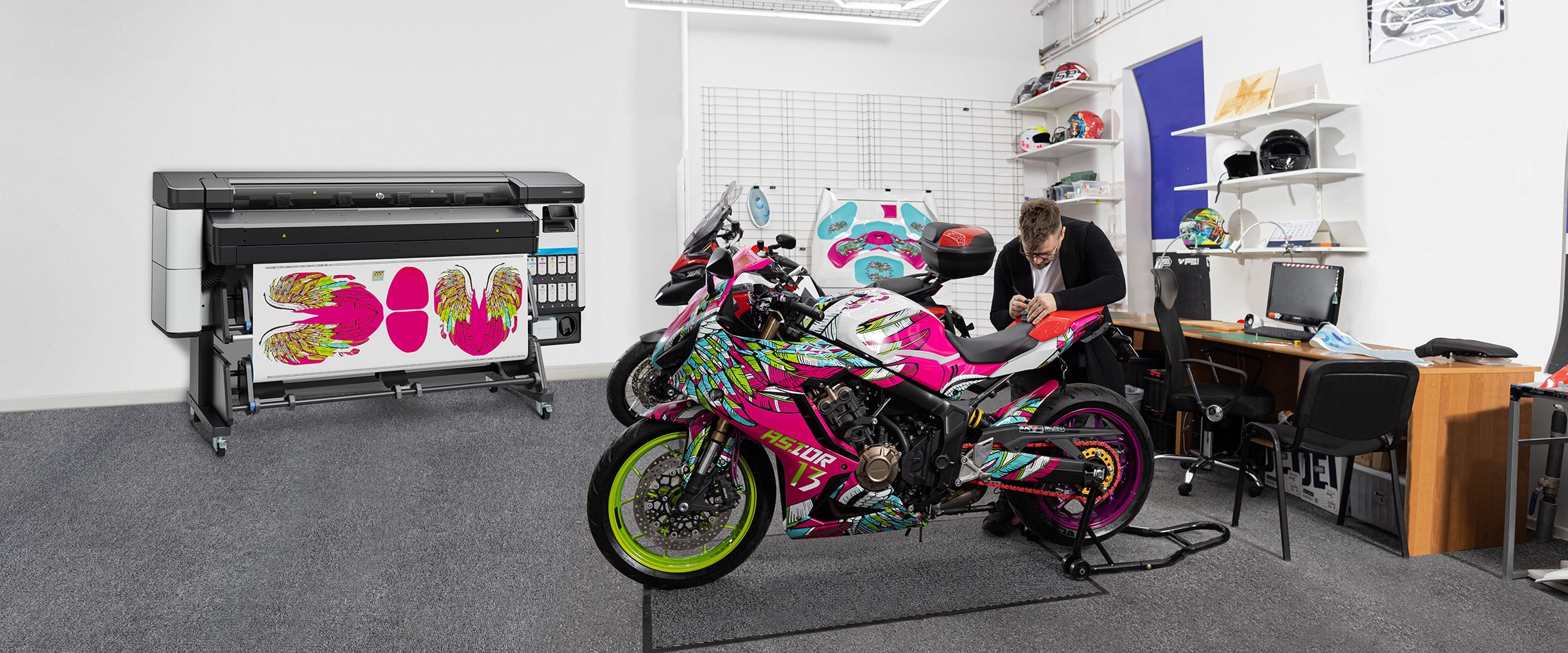 Person working on a motorcycle in a studio, next to the HP Latex 630 W printer