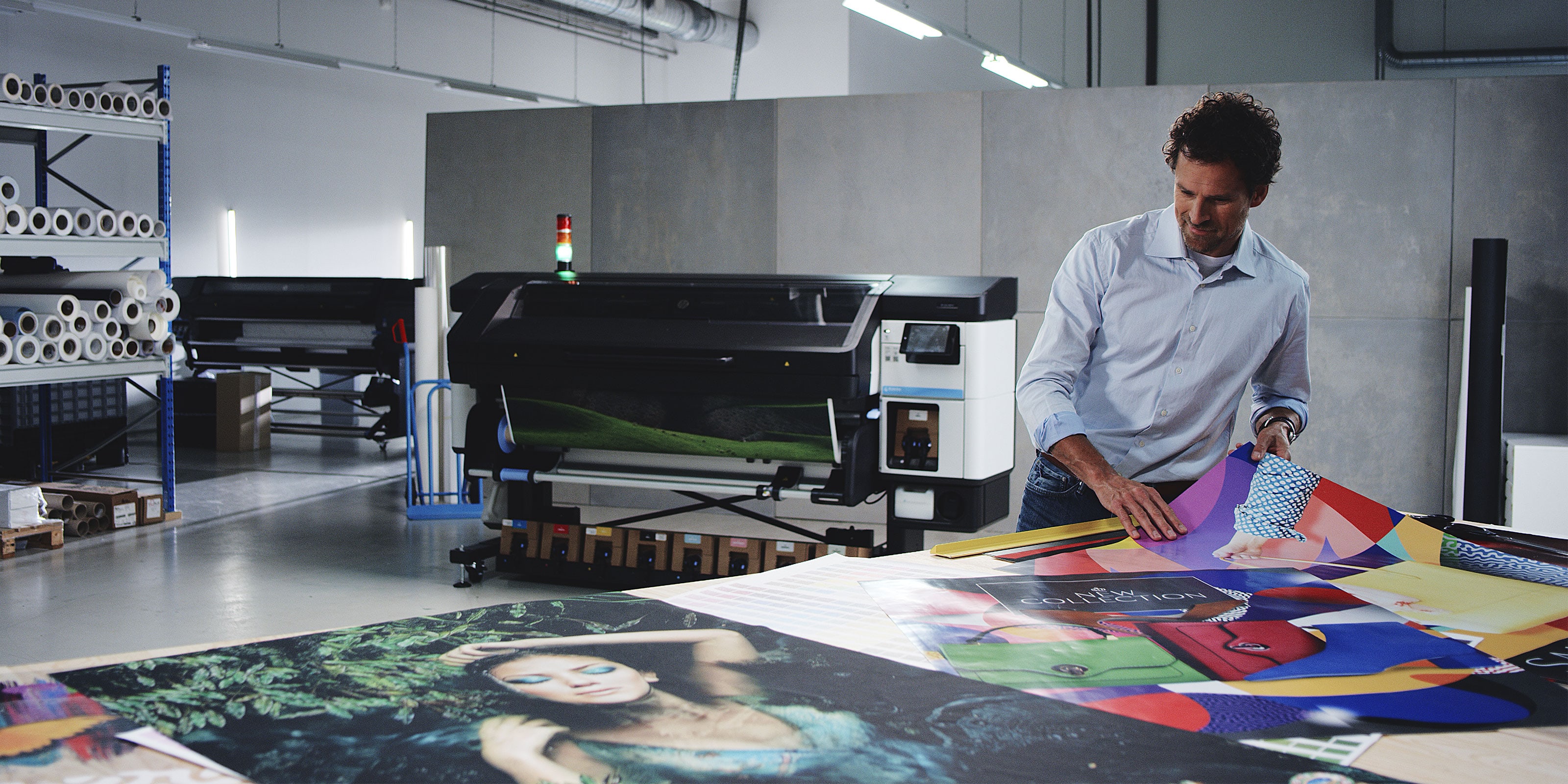 Person working with printed media over a table next to an HP Latex printer