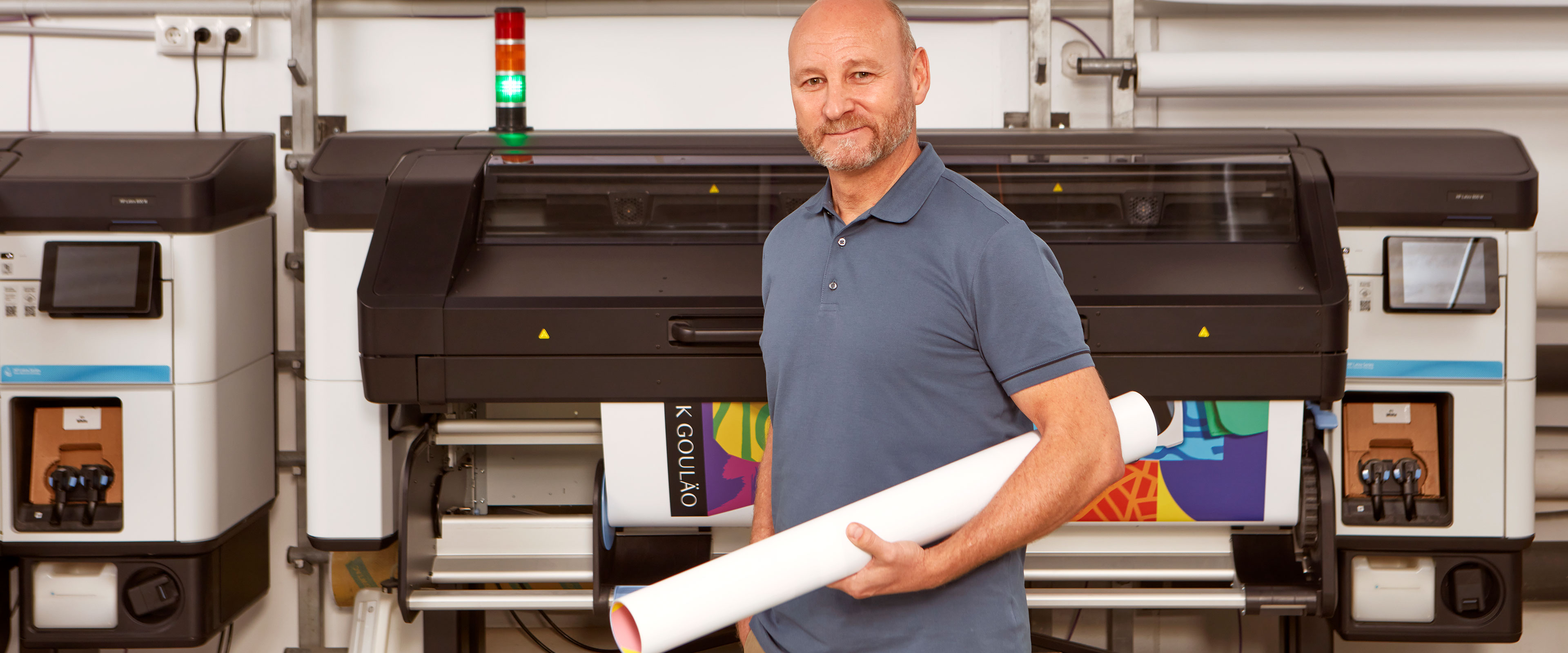 Person holding print media in front of an HP Latex printer