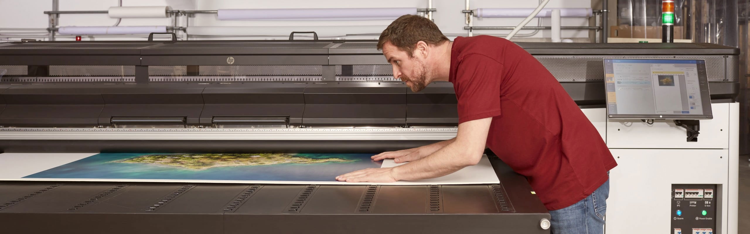 Man inspecting color print as it is in progress printing