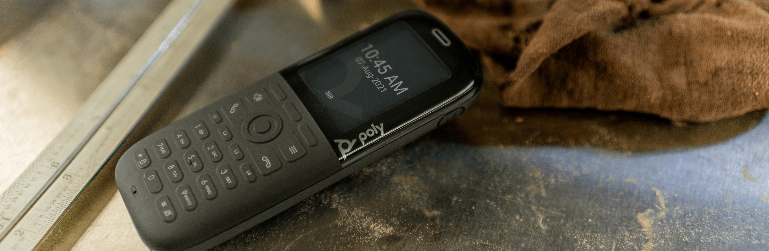 Poly Rove 30 wireless IP phone handset lying on a table in a fabrication workshop