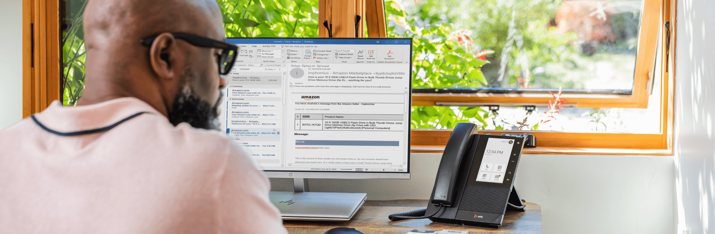 Back view of a man seated at home office desk using Poly CCX500 desk phone during a Microsoft Teams call 