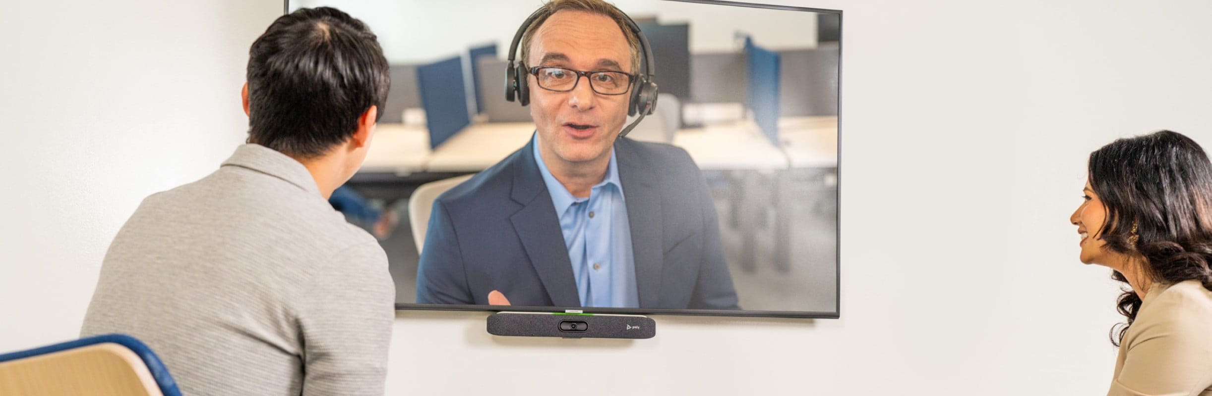 Man and woman in a video conferencing call with a man using headphones on the screen