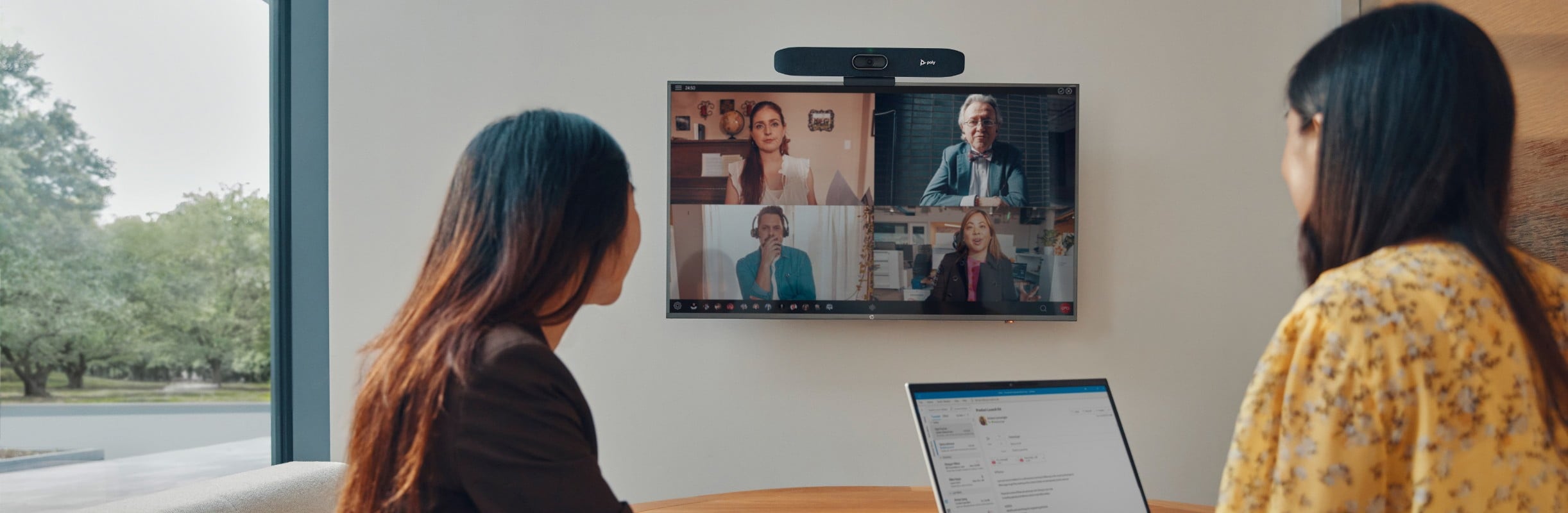 Two woman sitting at a table with laptops on a video conference call