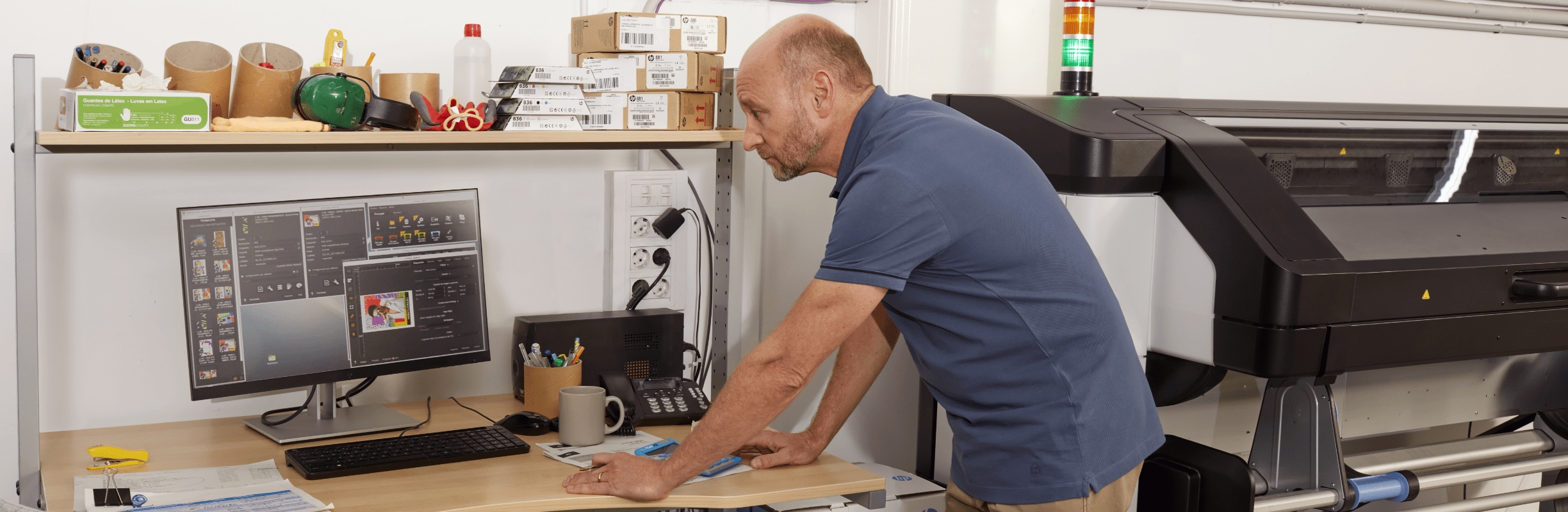 Person checking print software on an HP computer next to an HP Latex printer