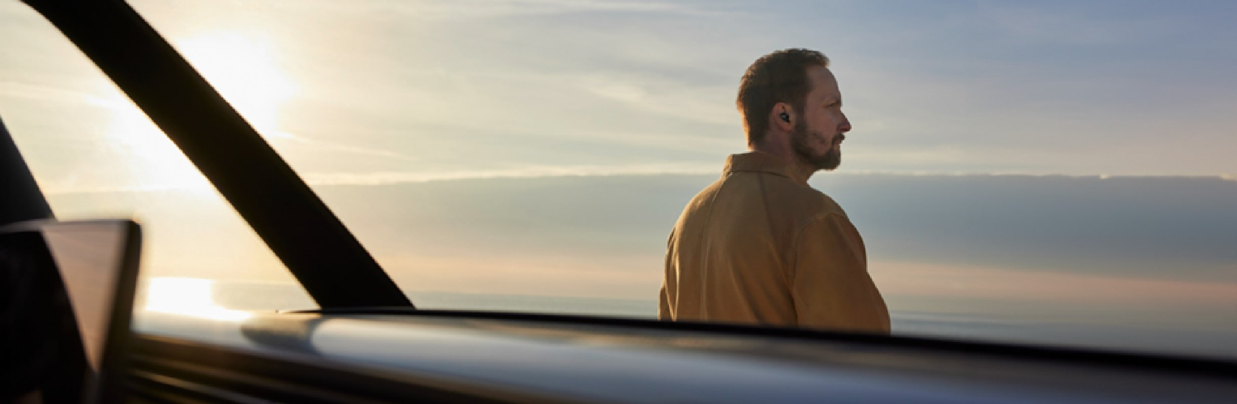 Man staring out into the horizon and wearing Poly Voyager Free 20 earbuds