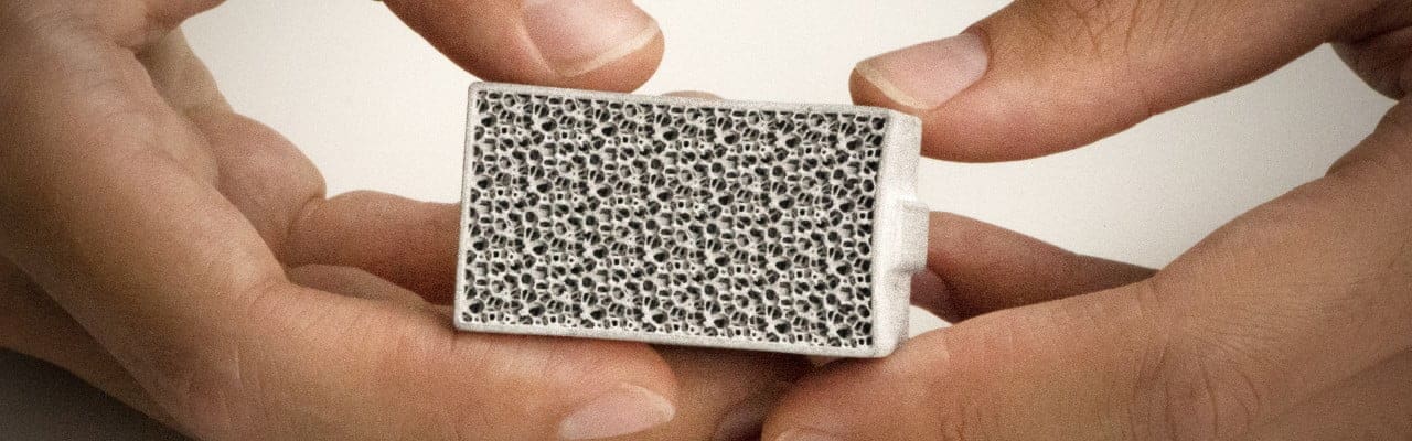 Two hands holding a metal 3D part - air filter from Schneider Electric