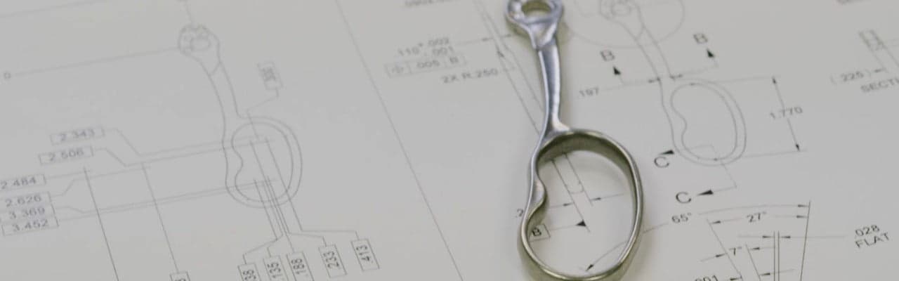 Metal 3D part laying over technical drawing from Parmatech