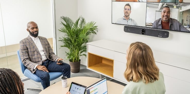 People in small meeting room on a video call using Poly Studio X70 video bar with TC8 touchscreen meeting controller