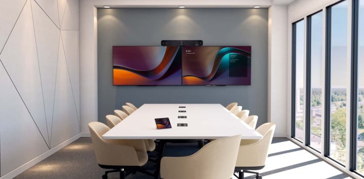 Large empty conference room with Poly Studio X70 video bar above monitors and touchscreen meeting controller on table Poly 