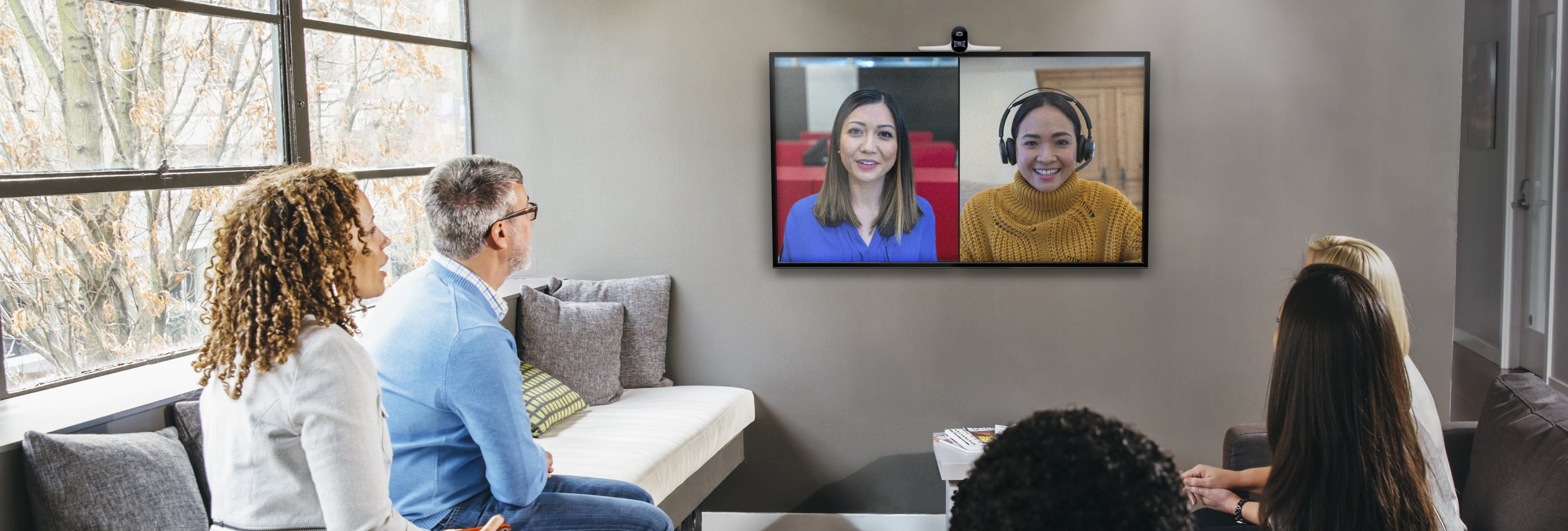 People in a meeting room using a Poly Studio conferencing system and video collaboration platform to engage with onscreen colleagues 