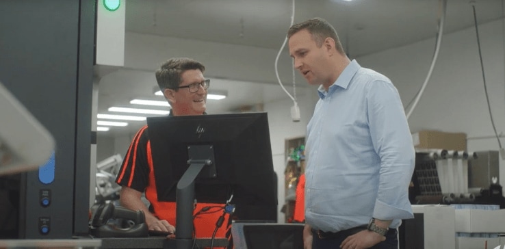 Two people standing next to a computer