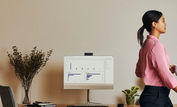 A woman walking passing aside an HP monitor.