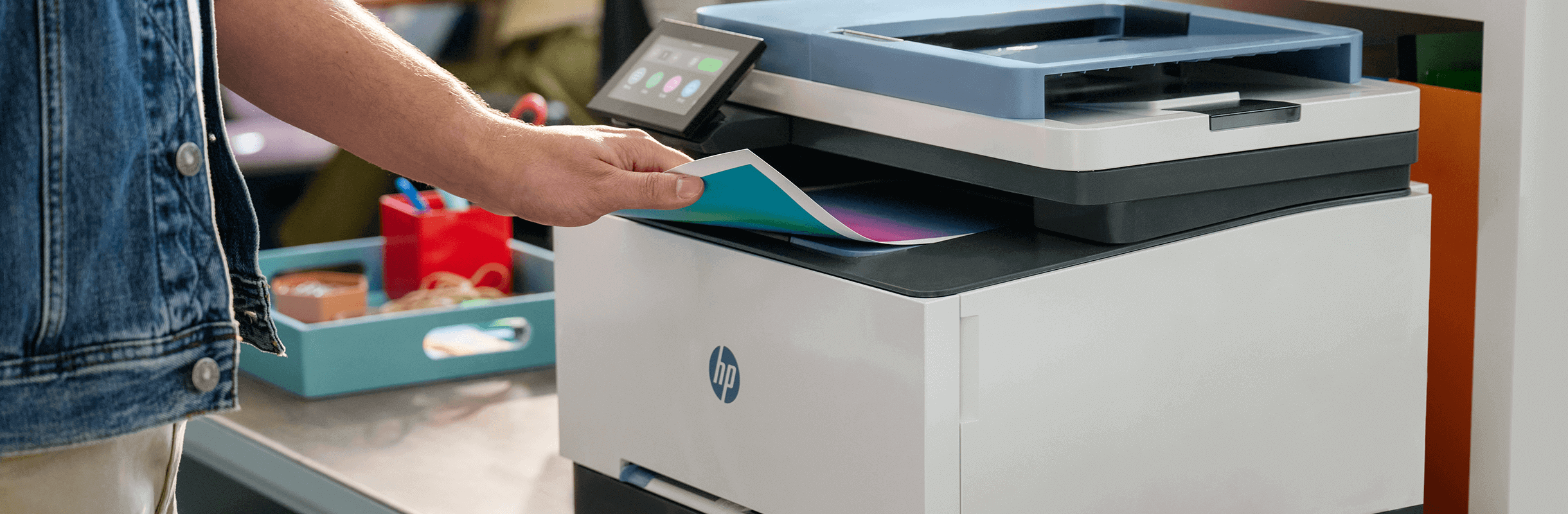 A man in the office takes out a color printout from an HP printer