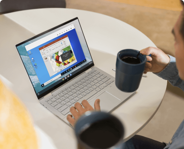 A man having a cup of coffee while he's working on his HP computer laptop.